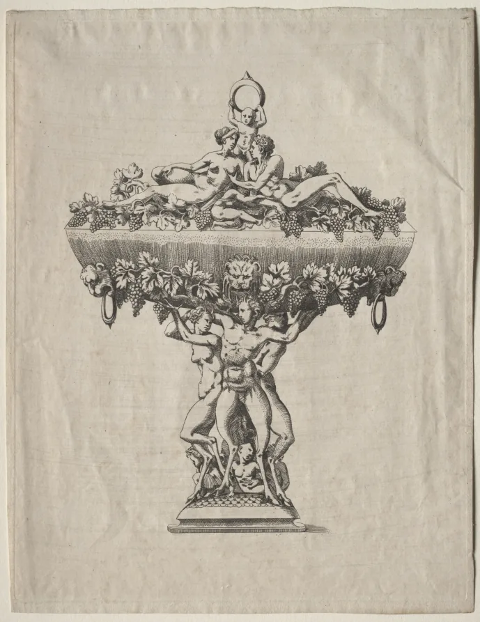 Kupferstich auf vergilbtem Papier: ein hoher Prunkpokal, dessen Fuß aus mehreren ineinander verschlungenen nackten Figuren besteht; auf dem breiten Rand der Schale liegen und lehnen weitere Gestalten, ringsum hängen Weinlaub und Trauben, seitlich zwei Ringgriffe, in der Mitte ein Löwenkopf.
