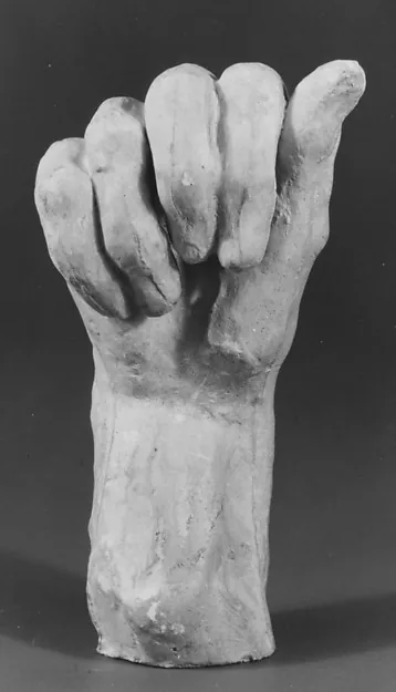 Schwarzweißfotografie einer aufrecht stehenden Hand aus hellem Material, die Finger halb eingerollt; am Handgelenk bricht sie glatt ab. Grauer Hintergrund.
