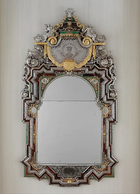 Großer Wandspiegel in reich verziertem Rahmen aus Silber und Gold, mit geschwungenem Aufsatz.